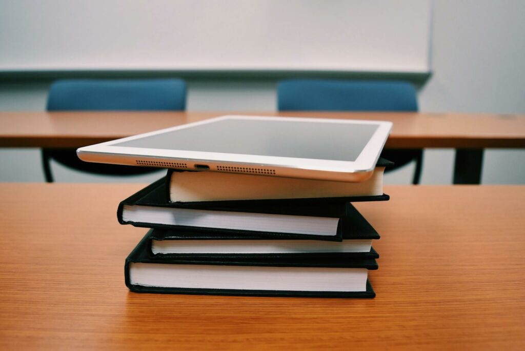 Silver Ipad on Stack of Books